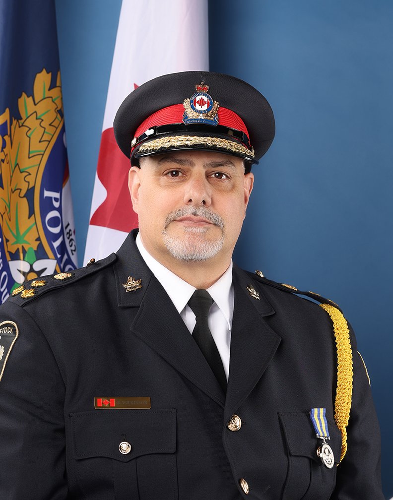 Portrait of Chief Wilkinson in Number 1 Dress in front of a flag.